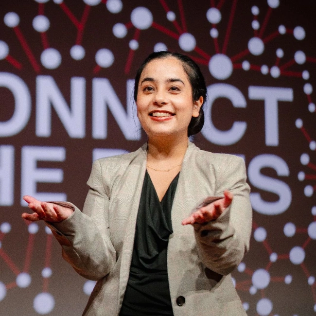 Professional woman beside “Connect the Dots” sign representing the minds behind Zenith School of Leadership